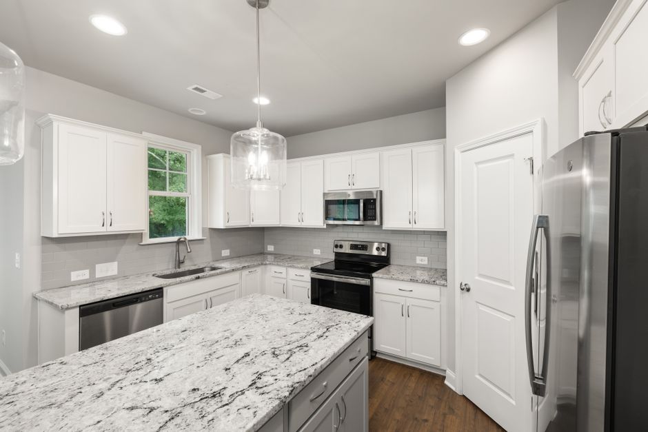 Spacious modern kitchen featuring white cabinets, granite countertops, and stainless steel appliances.