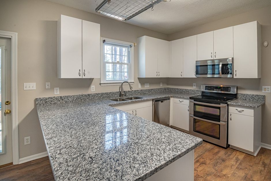 Sleek kitchen design featuring granite countertops, white cabinets, and stainless steel appliances.