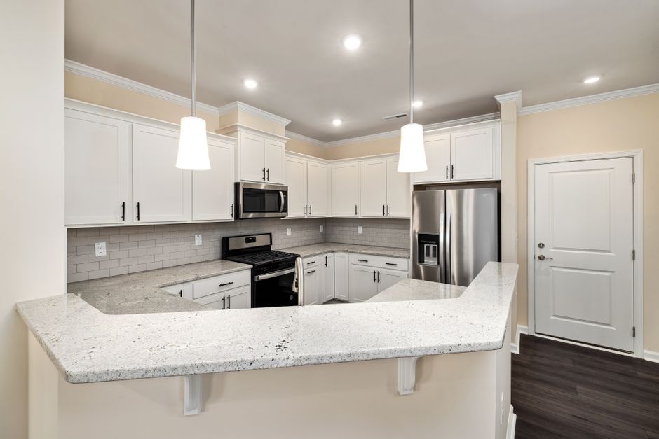 Sleek contemporary kitchen featuring white cabinets and granite countertops.